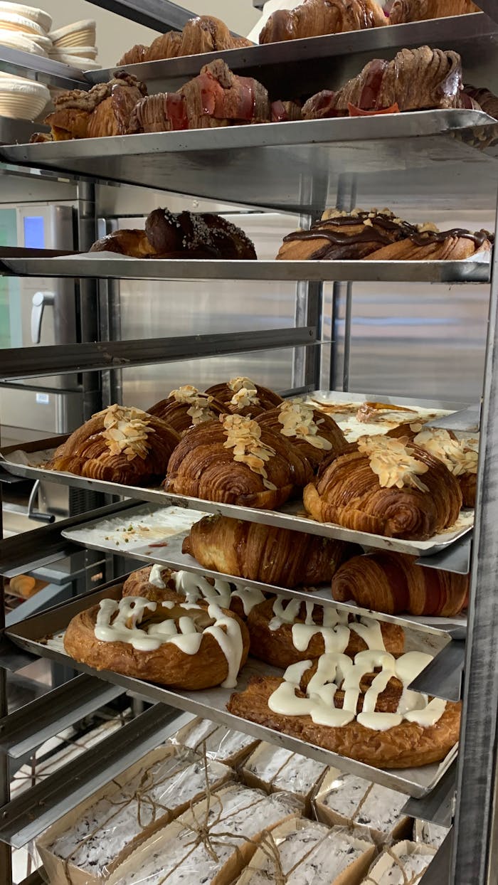 who-we-are Delicious assortment of pastries displayed on industrial bakery shelves, fresh and enticing.